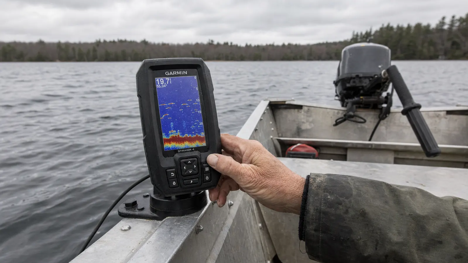 Hand adjusting the mounting bracket of a Garmin Striker 4 fish finder on a boat console