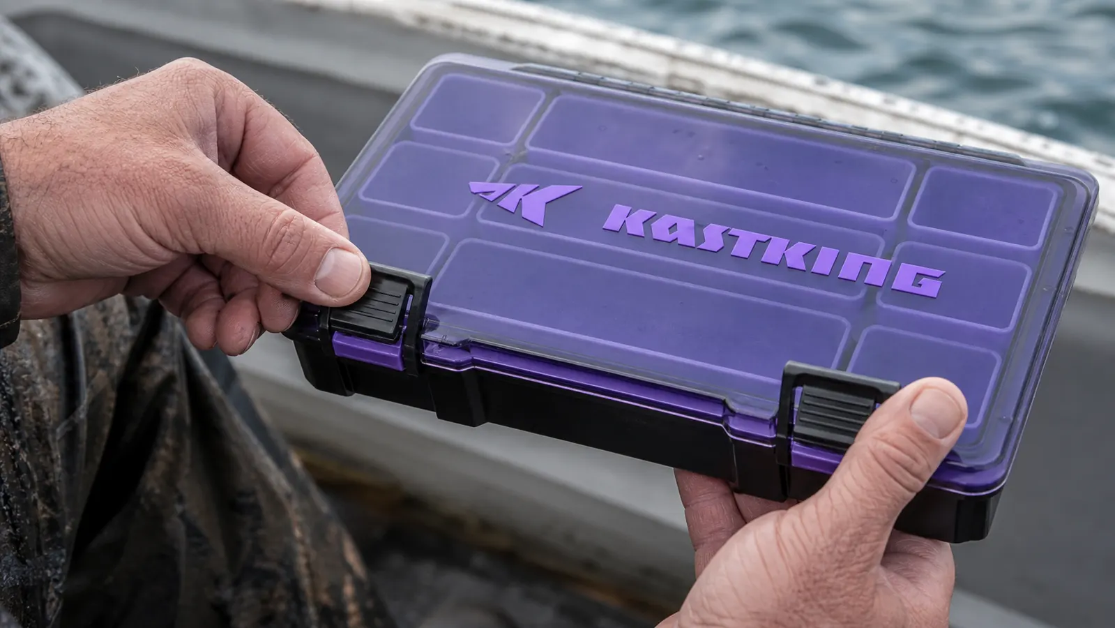 Close-up of a hand pressing the latch closed on a KastKing tackle tray to show the double-latch design